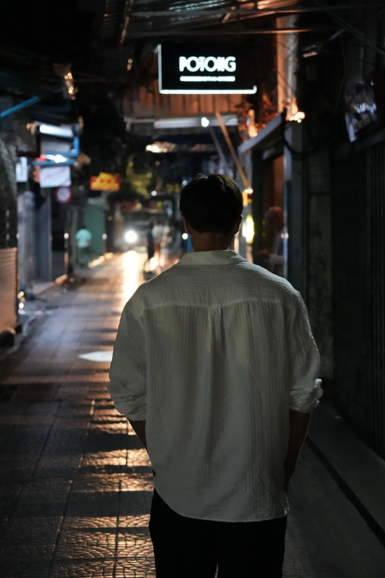 Olaf seen from behind, walking down a lit street at night